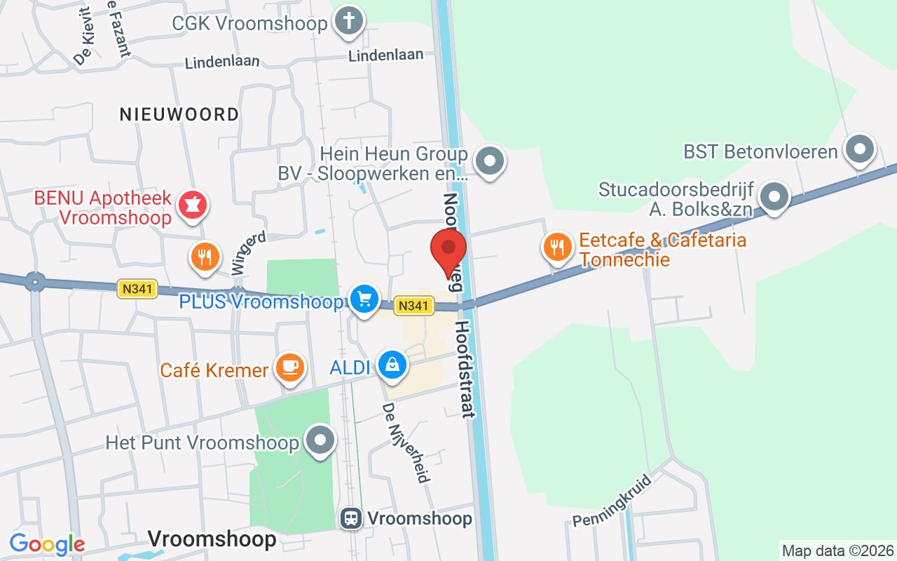 Een foto van de ingang van de Dorcas Winkel in Vroomshoop, met zicht op de winkel en omgeving.