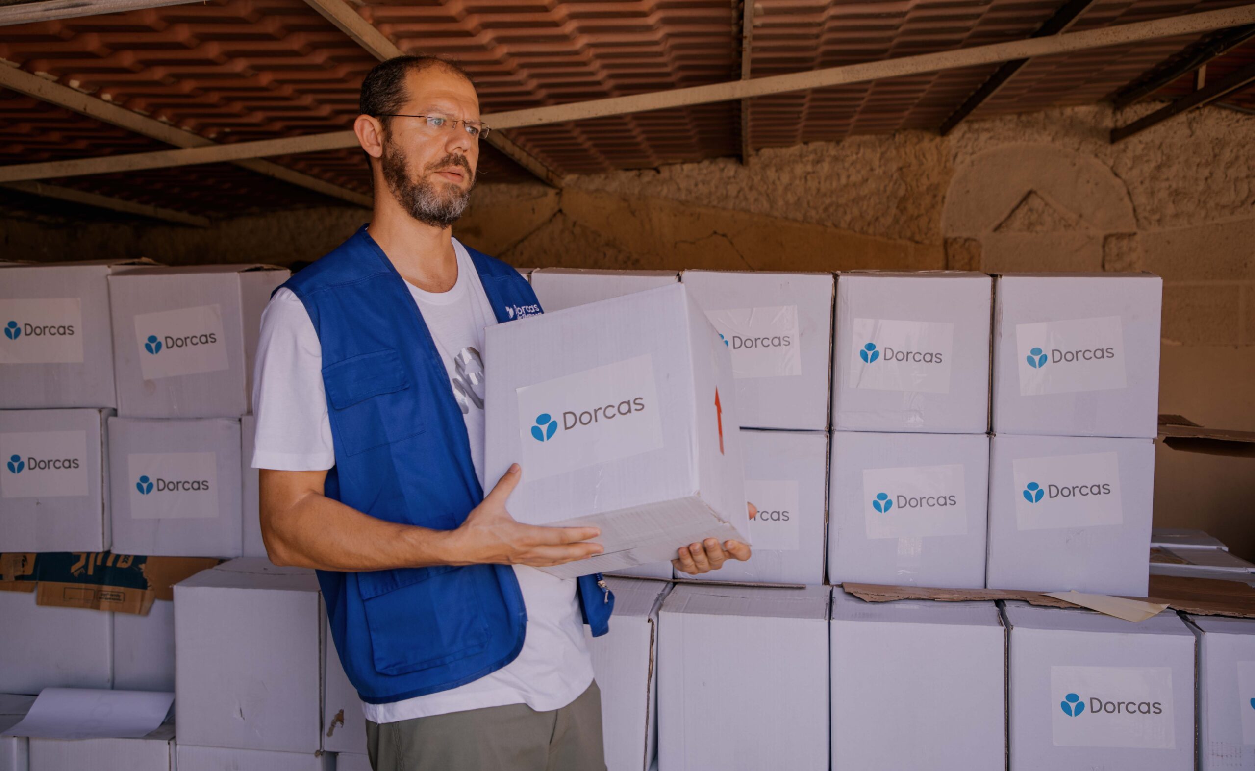 Het CNC, christelijk noodhulpcluster komt in actie met Dorcas als christelijk goed doel actief in landen met grote nood. Op de foto een medewerker die voedsel uitdeelt met een grote witte doos met daarin de benodigheden om te overleven.