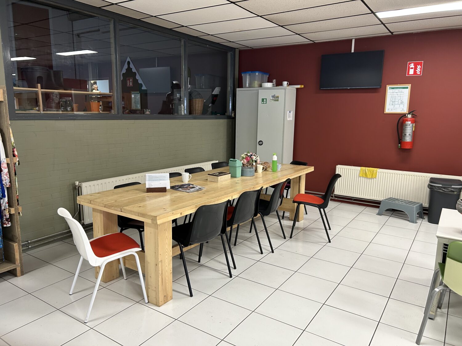Ontspanningsruimte bij Dorcas met eettafel en stoelen, decoratieve bloemen en informatiebrochure op tafel, in een gezellige omgeving voor ontmoetingen en samenkomen.