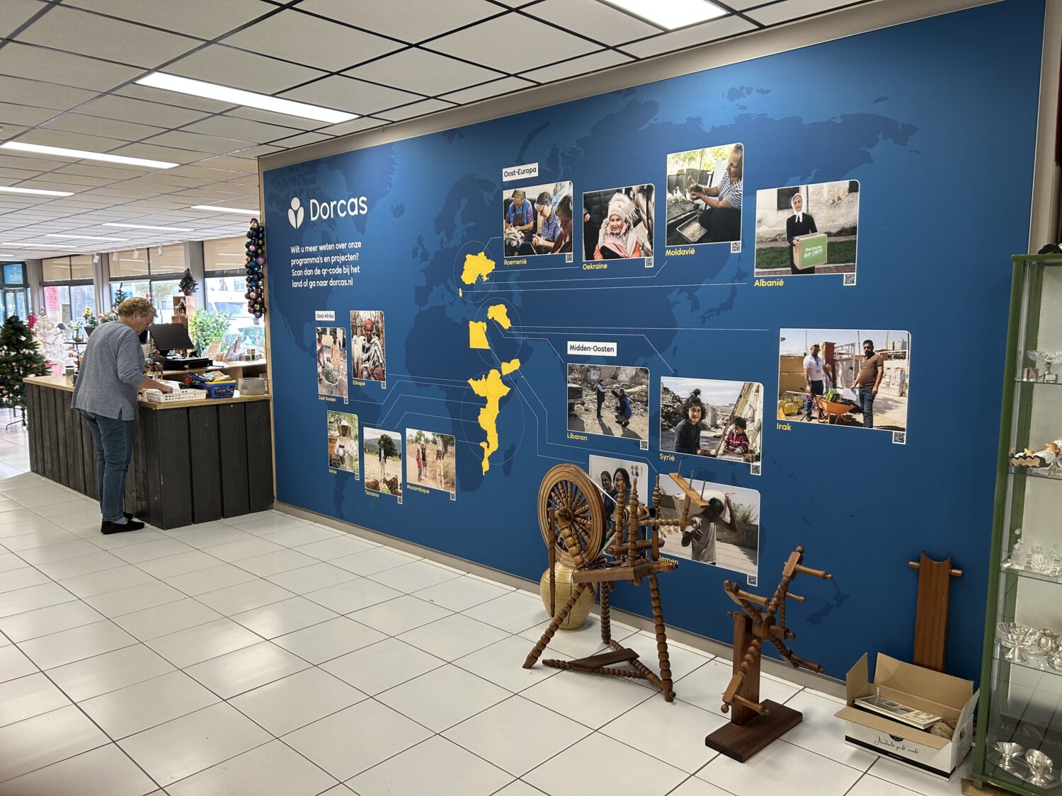 Dame een donorbijeenkomst bij Dorcas met een wereldkaart en projectfoto's.