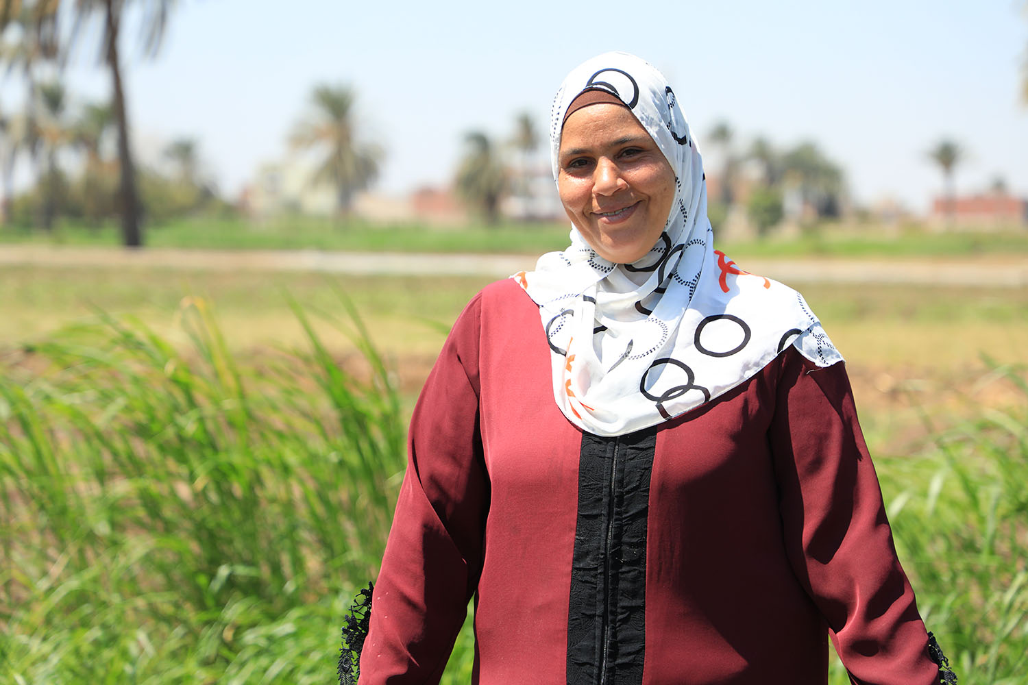 Vrouw met hoofddoek in een groen landschap in Egypte.