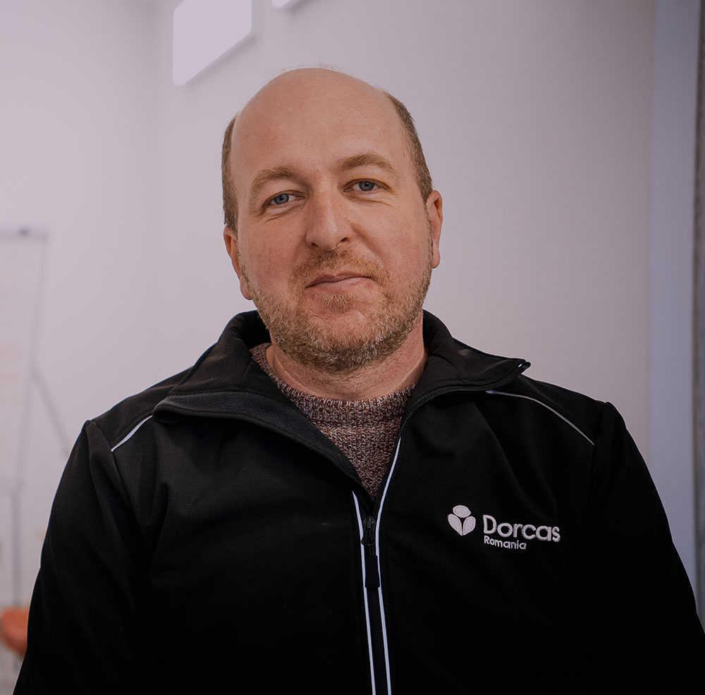 Man in zwarte Dorcas Romania jas, close-up portret, vriendelijke uitstraling, professionele achtergrond.