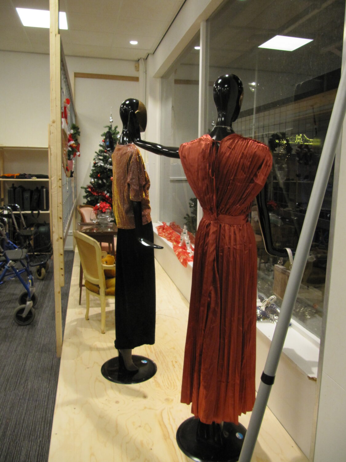 Elegante avondjurk en modieuze top op mannequin, winkeldecor met kerstversiering, showroom met modeaccessoires en winterse sfeer bij Dorcas.