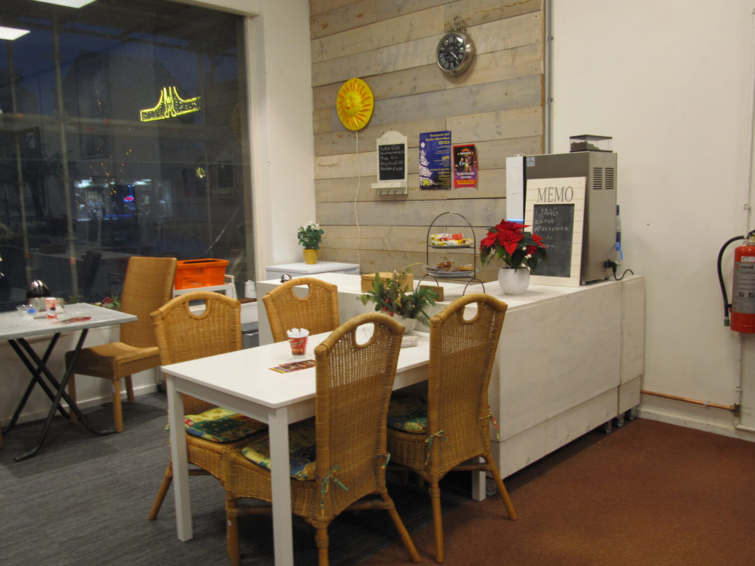 Gezellig interieur van een café of restaurant met witte tafels en rieten stoelen, decoratie en een menubord met feestdagen sfeer.