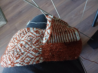 Veelzijdige breiwerk op naald, klaar voor verdere afwerking, met verschillende texturen en kleuren voor een uniek handgemaakt project.