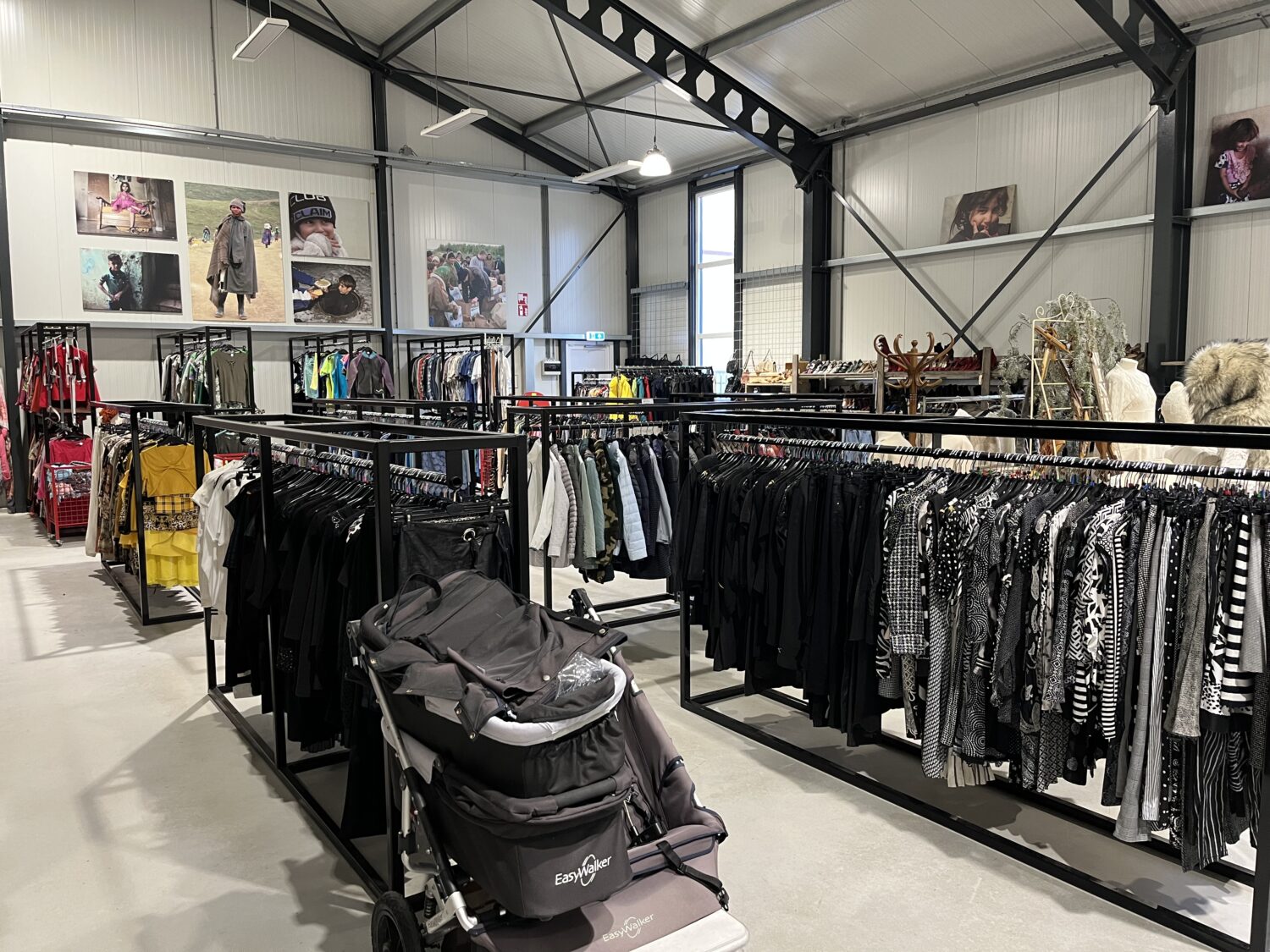 Duurzaam tweedehands kledingwinkel met diverse kledingrekken en affiches, geschikt voor hergebruik en milieuvriendelijk shoppen.