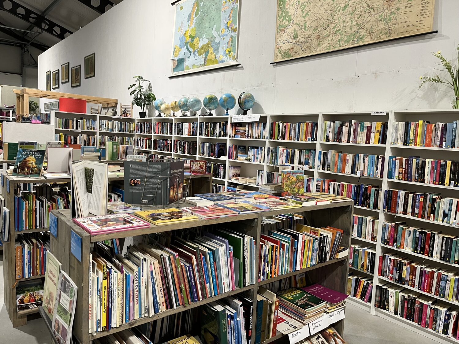 Een ruime boekwinkel vol kleurrijke boeken en wereldkaarten, ideaal voor boekliefhebbers en educatieve doeleinden.