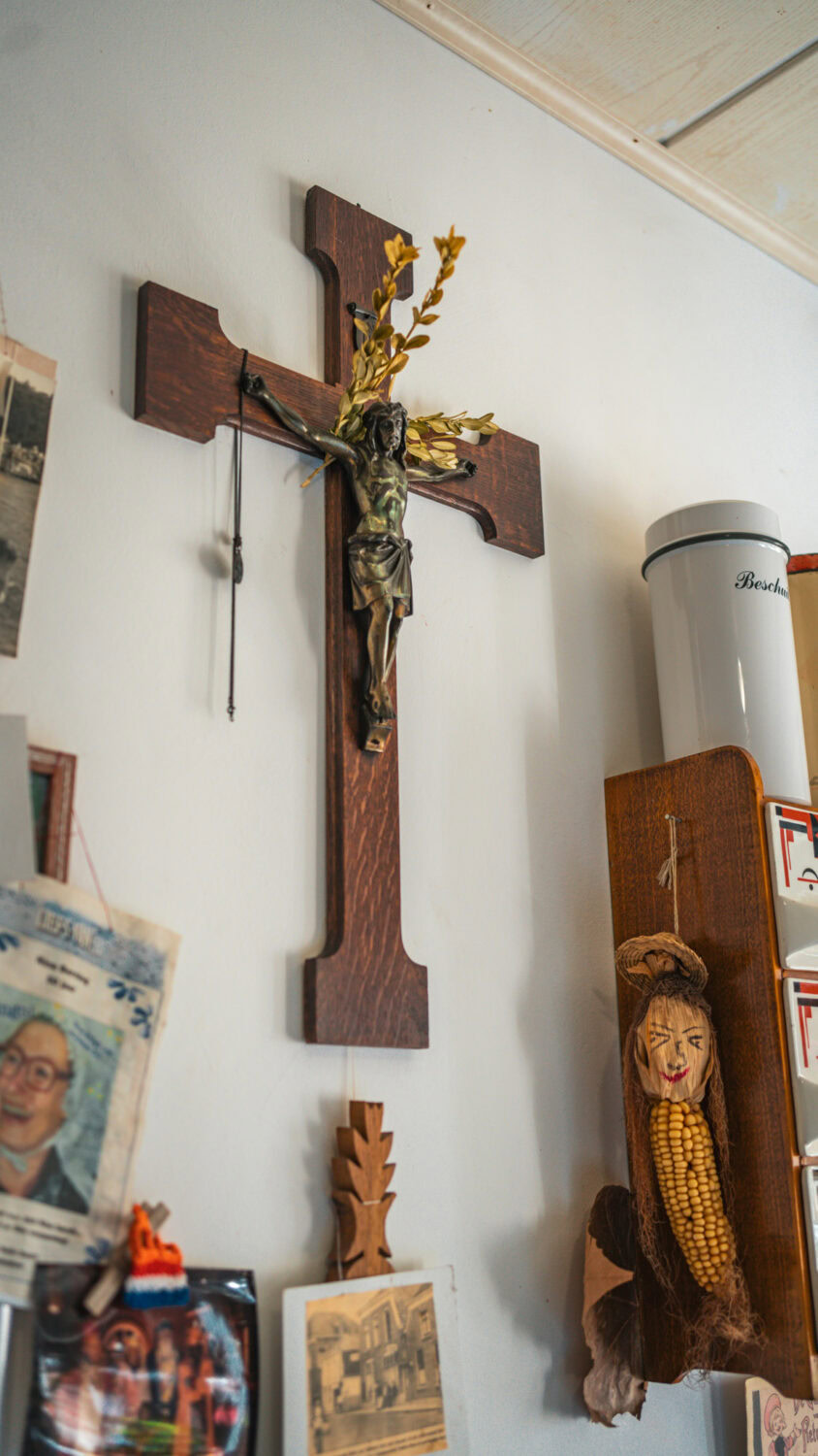 Houten kruis met Jezusfiguur en bloemen, religieus wanddecoratie in interieur.