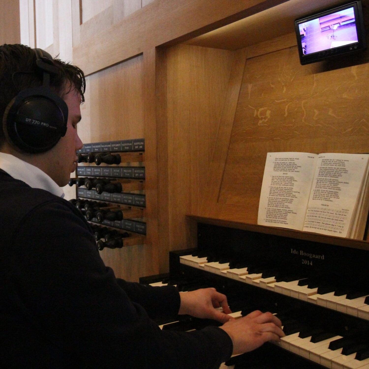 Muzikant speelt piano tijdens kerkdienst bij Dorcas, met zangerige bladmuziek en orgelknoppen op de achtergrond.