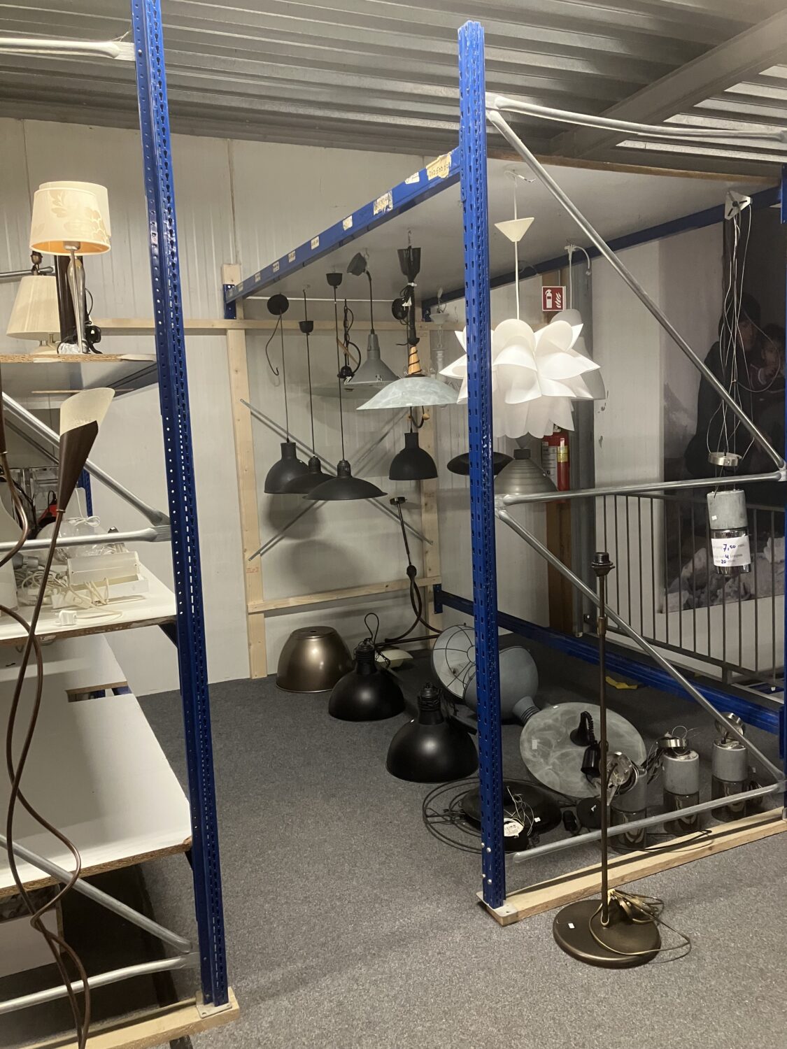 Grote collectie van diverse vloerlampen, hanglampen en plafondlampen in een warehouse of verlichtingswinkel.