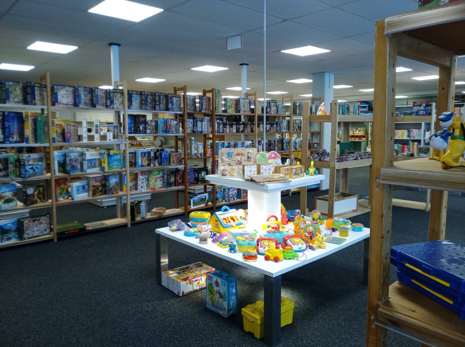 Kleine speelgoedauto's en kinderspeelgoed op een witte tafel in een goedgevulde tweedehands winkel.