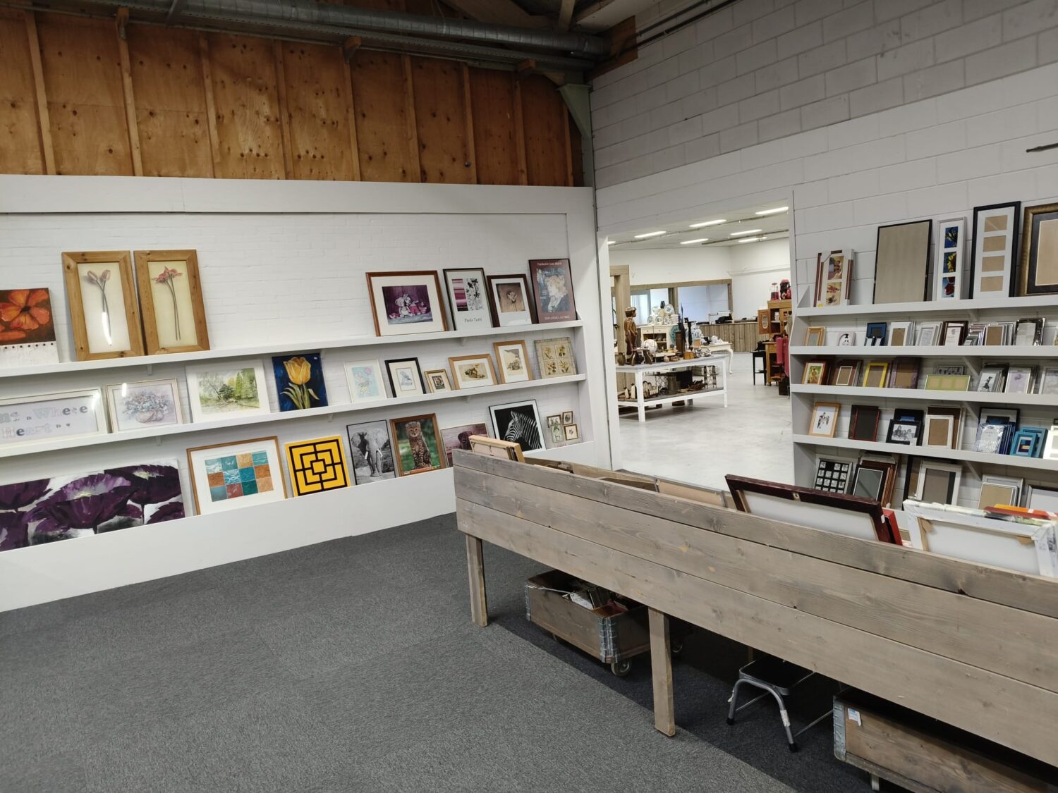 Kunst- en decoratiewinkel met diverse schilderijen, foto’s en decoratieve items, geschikt voor interieurdecoratie en kunstliefhebbers.