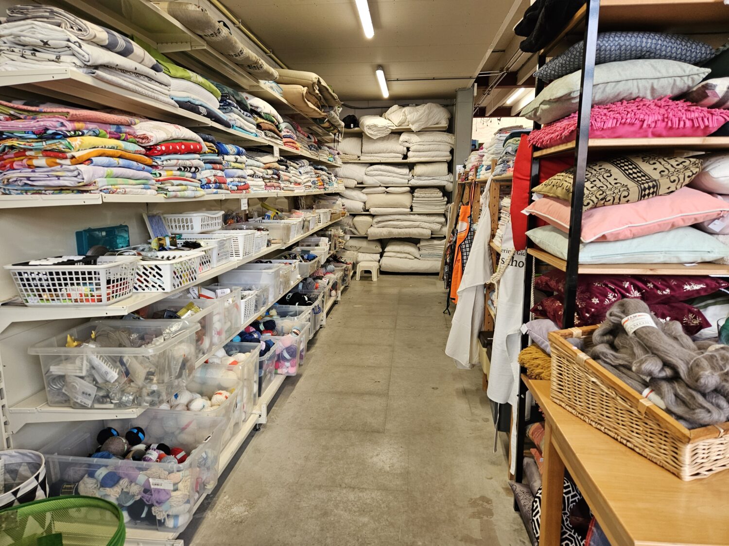 Een overzicht van een winkel met een breed assortiment aan beddengoed, kussens, en huishoudelijke artikelen, ideaal voor hergebruik en duurzame consumptie.