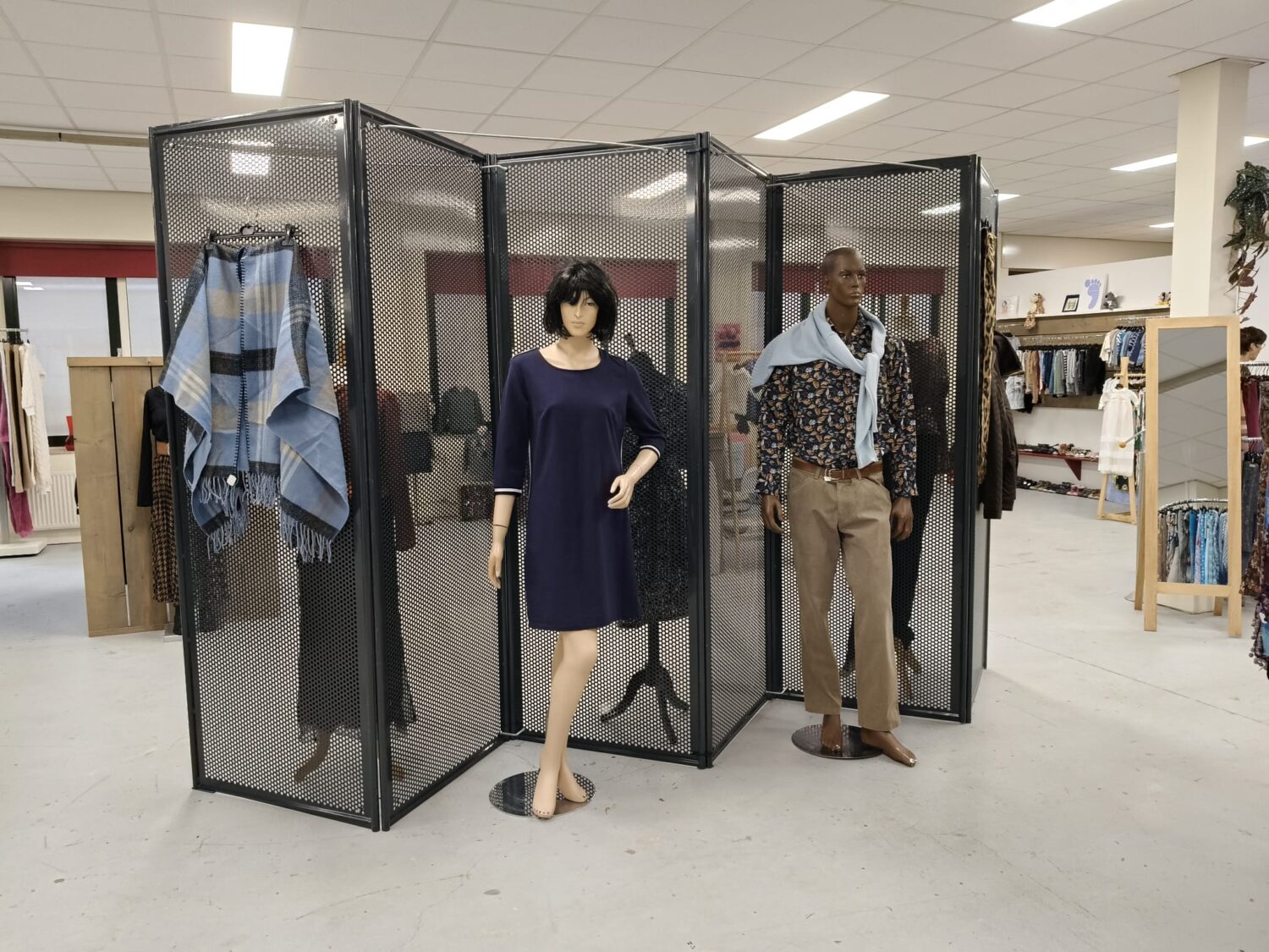 Een overzicht van mannequins die kleding tonen in een winkelomgeving, met diverse outfits en accessoires, bedoeld om klanten te inspireren en het assortiment te presenteren.