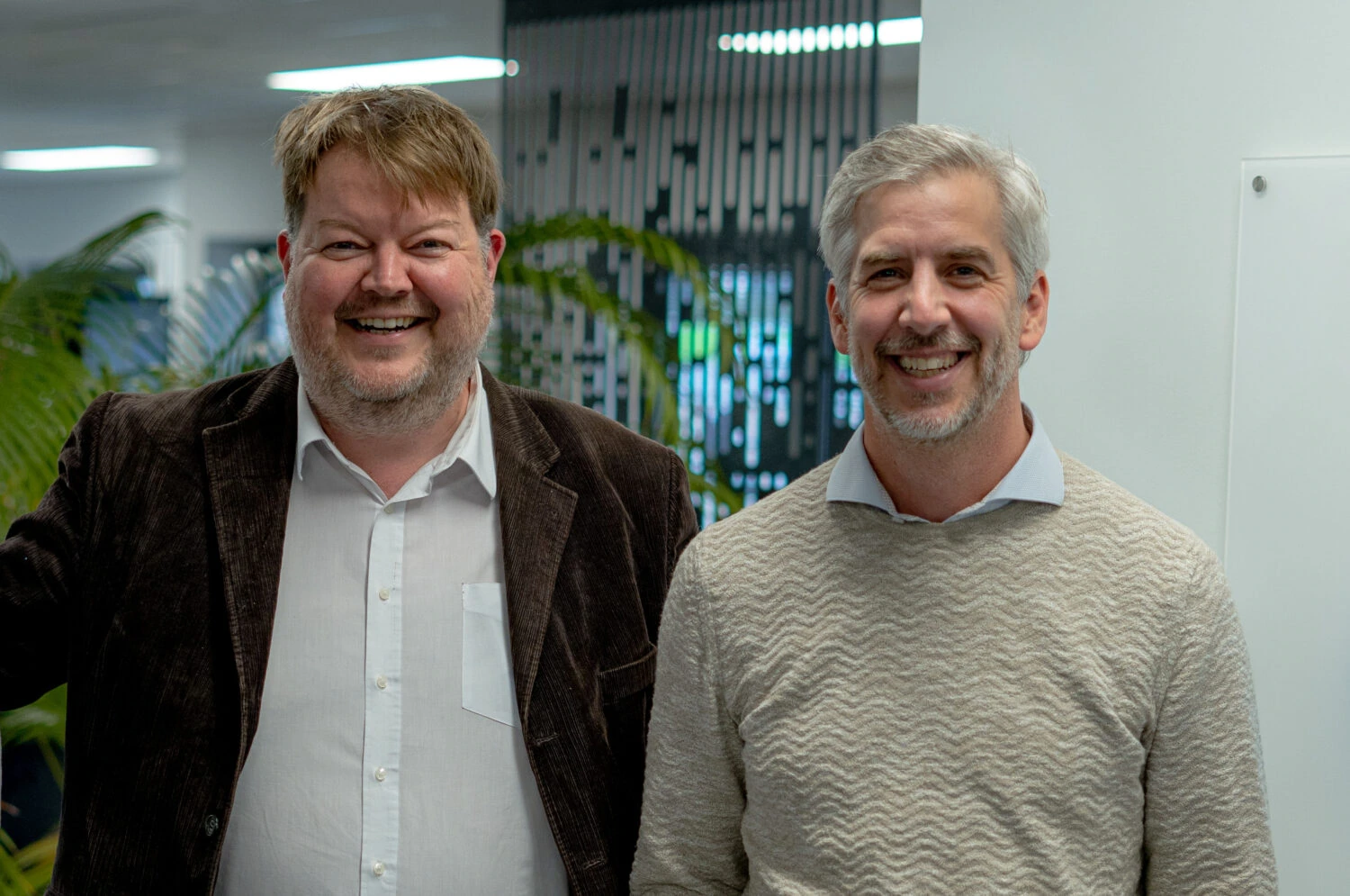 Twee tevreden mannen in een kantooromgeving, die de overgang van ondernemer naar relatiebeheerder bespreken, met een professionele en vriendelijke uitstraling.