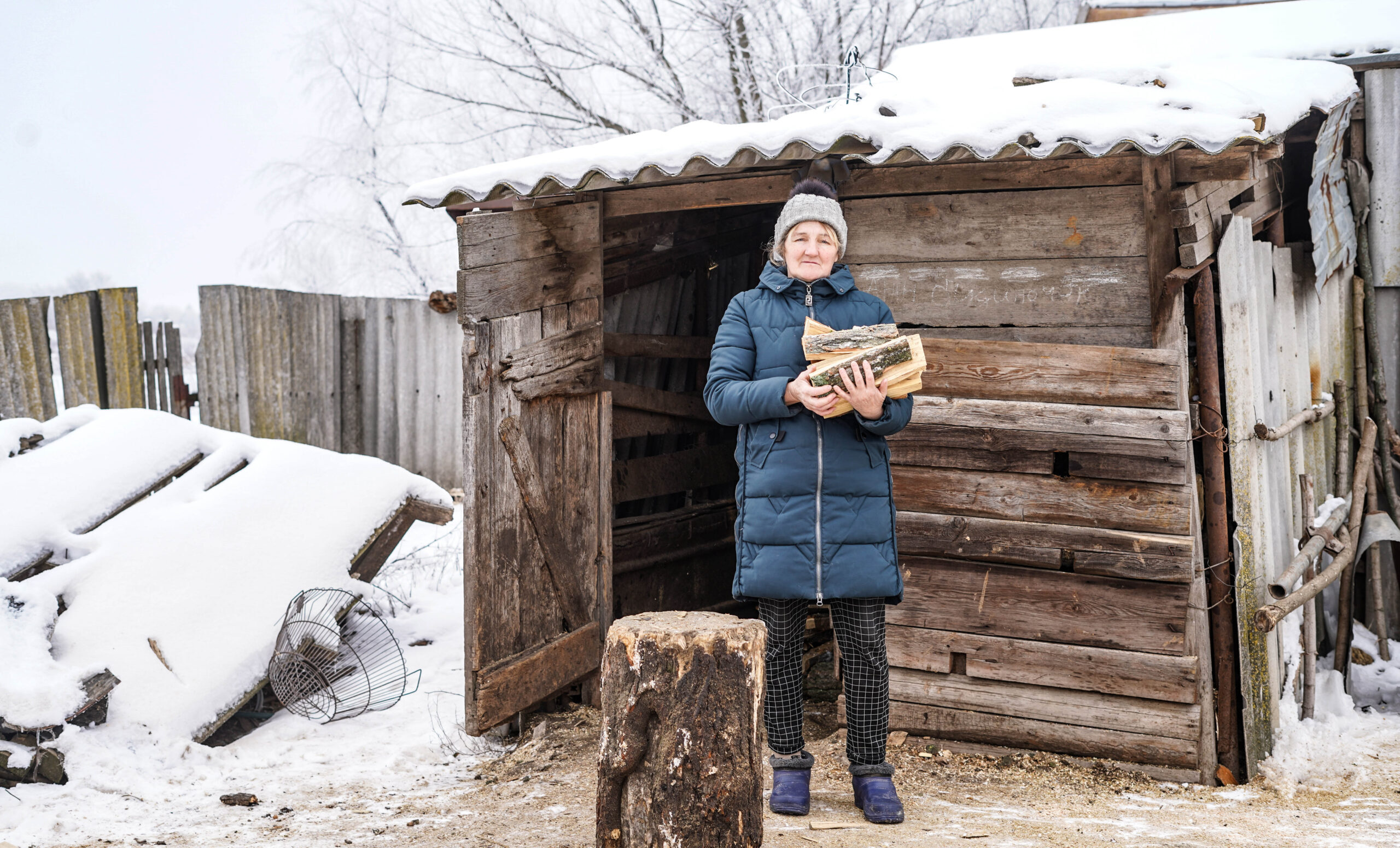vrouw Tetiana hakt hout in de sneeuw in Oekraine