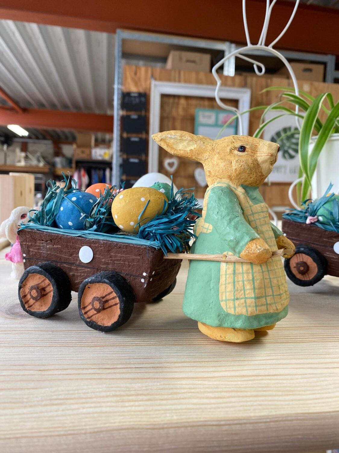 Een houten paashaas met een mandje vol gekleurde eieren en decoraties, geschikt voor paasdecoratie en ambachtelijke feestversiering.