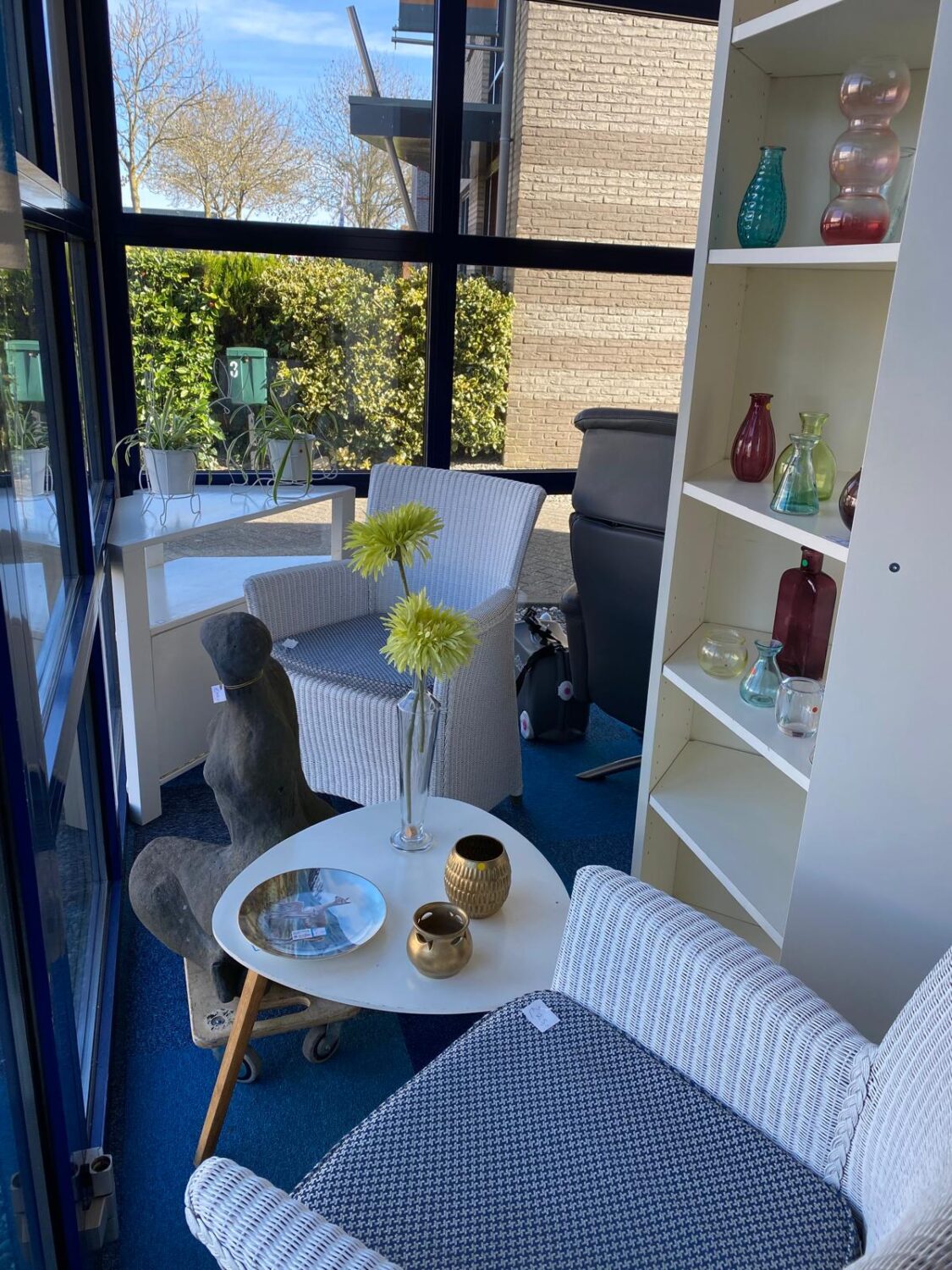 Een gezellige zithoek met grote ramen, kleurrijke decoraties en comfortabele meubels, ideaal voor ontspanning en sociale bijeenkomsten.