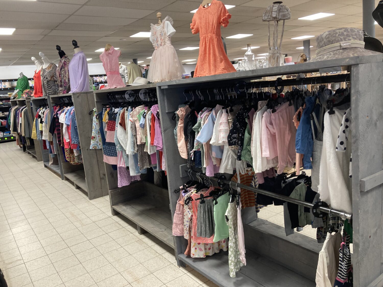 Kinderkledingwinkel met diverse outfits voor kinderen, overzicht van kledingrekken en mannequins in een winkel.
