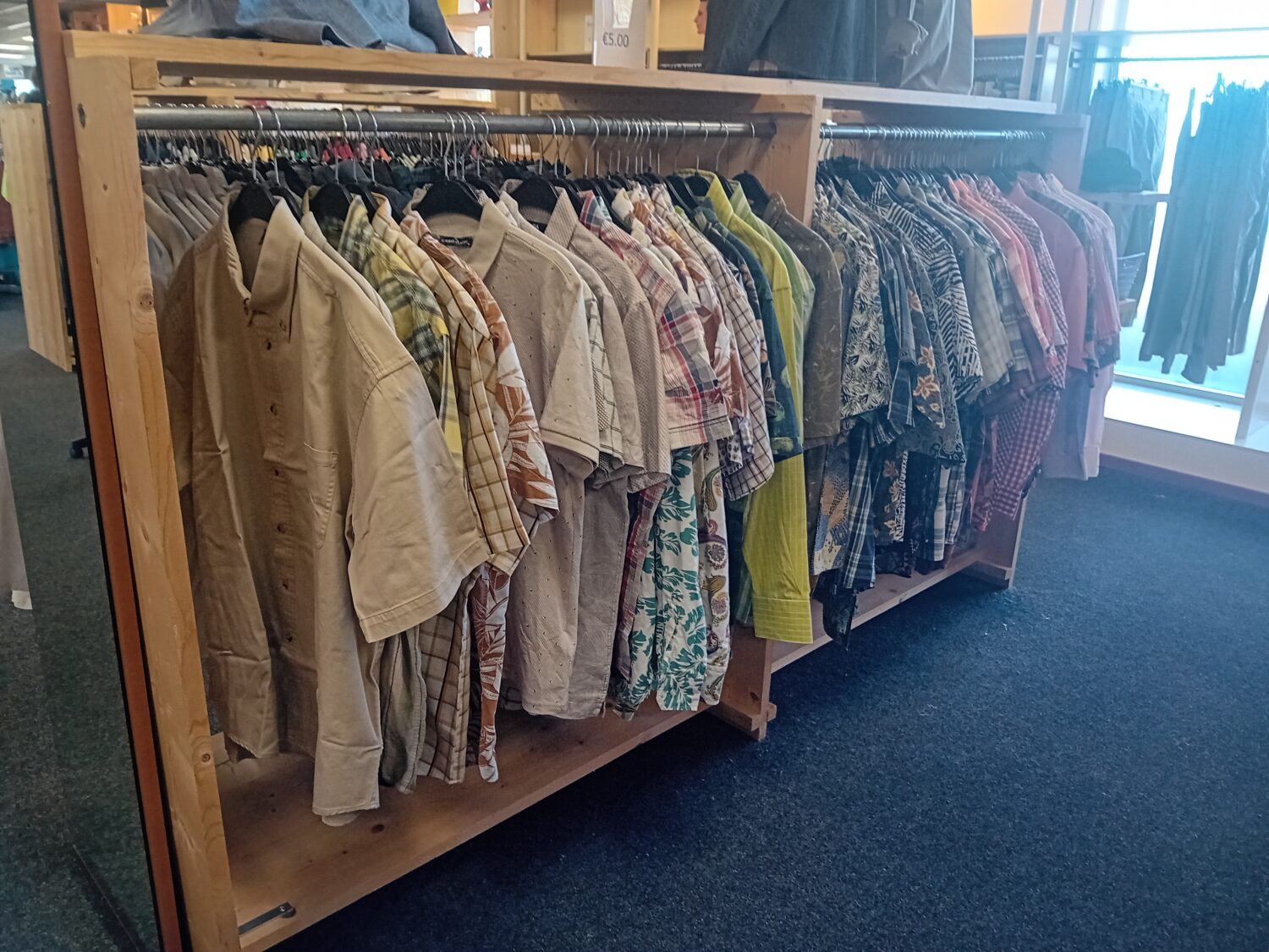 Een kledingrek met een assortiment overhemden en shirts in verschillende kleuren en patronen, geschikt voor hergebruik en duurzame mode.