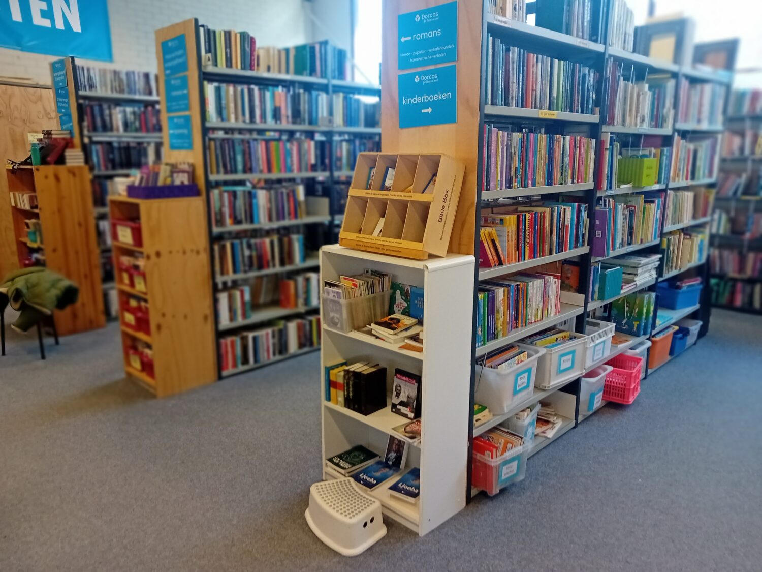 Een boekenkast gevuld met diverse boeken en educatief materiaal in een bibliotheek.
