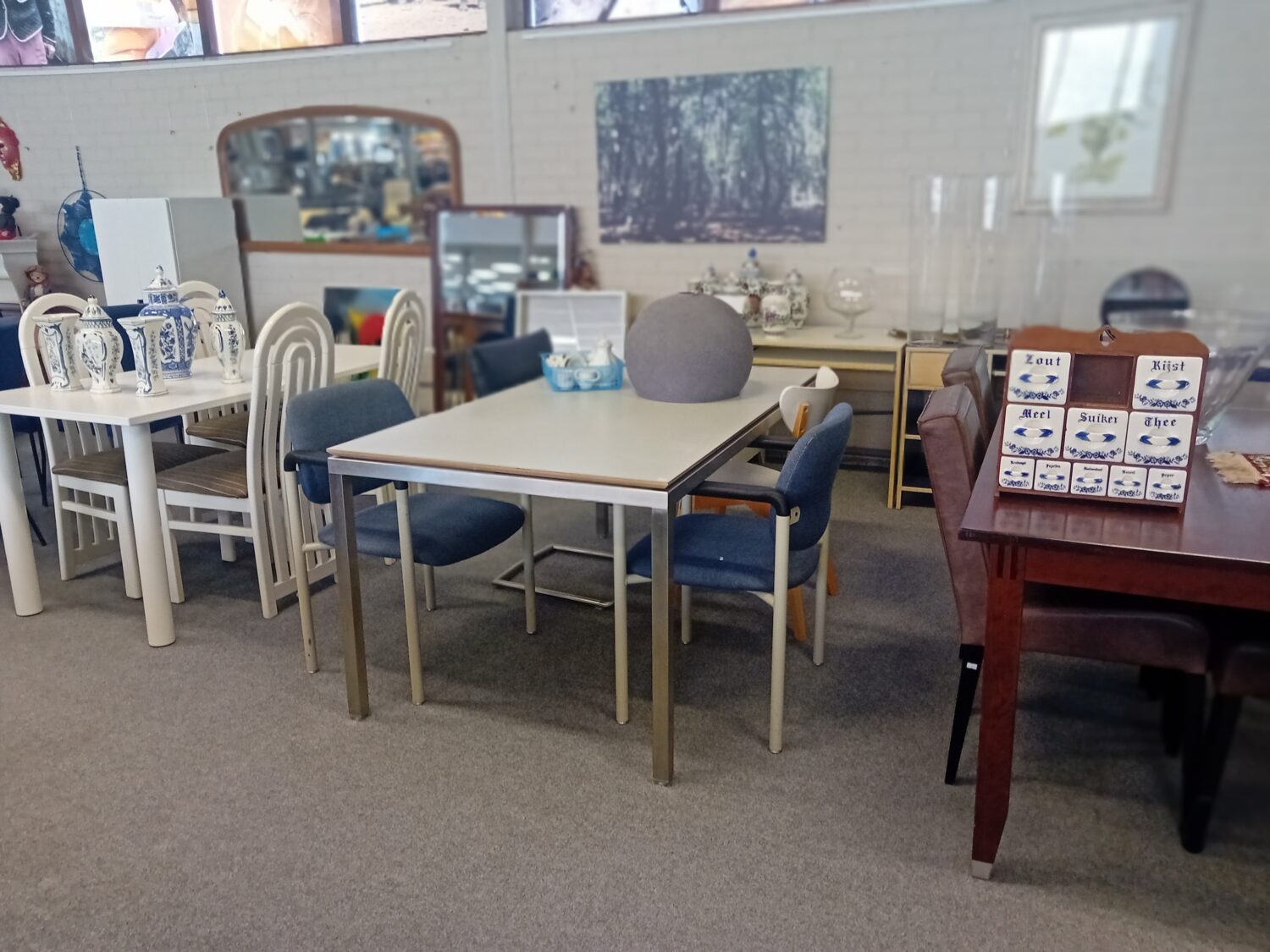 Een overzicht van diverse meubels en decoratieartikelen in een winkel of showroom, geschikt voor hergebruik en duurzame inrichting, aangeboden door Dorcas.