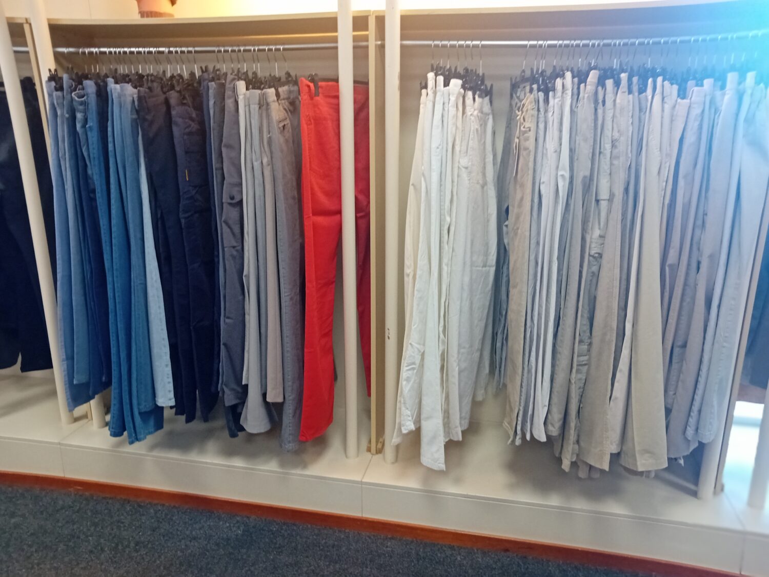 Kledingrekken met verschillende gekleurde broeken en pantalons, geschikt voor goede doelen en sociale initiatieven, aangeboden door Dorcas.