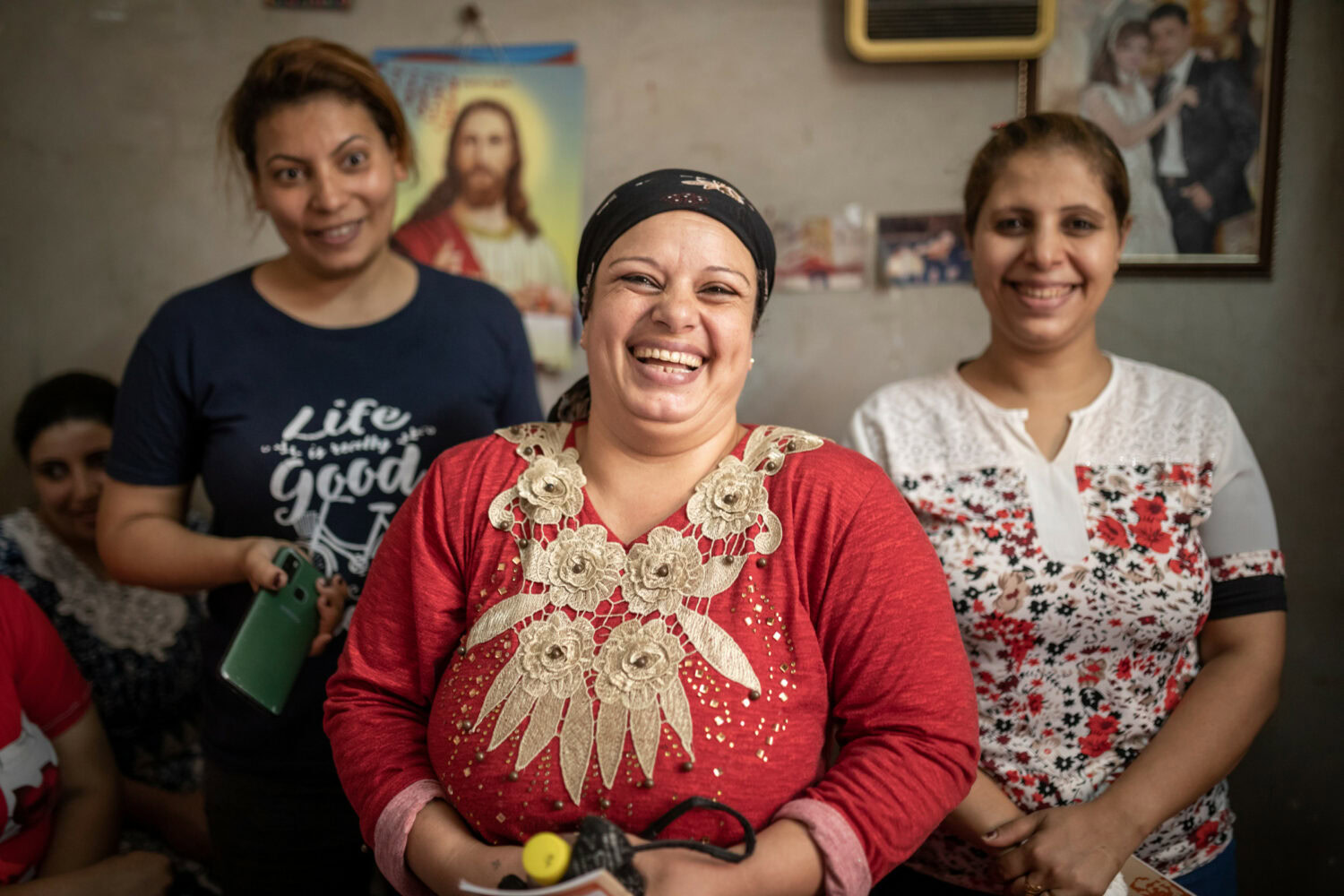 Vrouwen lachen en glimlachen in een gemeenschapssituatie, symboliseert hoop en verbondenheid in landen waar Dorcas actief is.