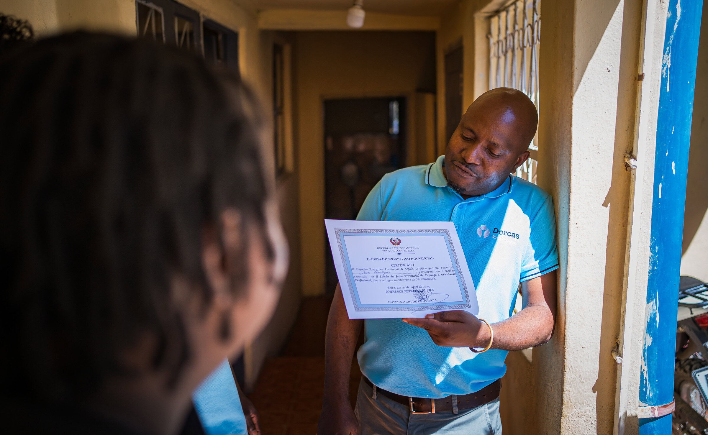 Een Dorcas-medewerker overhandigt een certificaat aan een donor, symboliseert het geven van giften met belastingvoordeel via Dorcas.