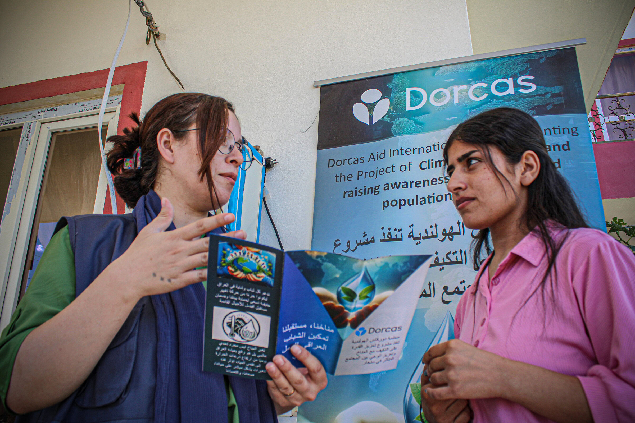 Een vrouw krijgt informatie over het Dorcas-project in Irak, gericht op klimaatverandering en bewustwording.