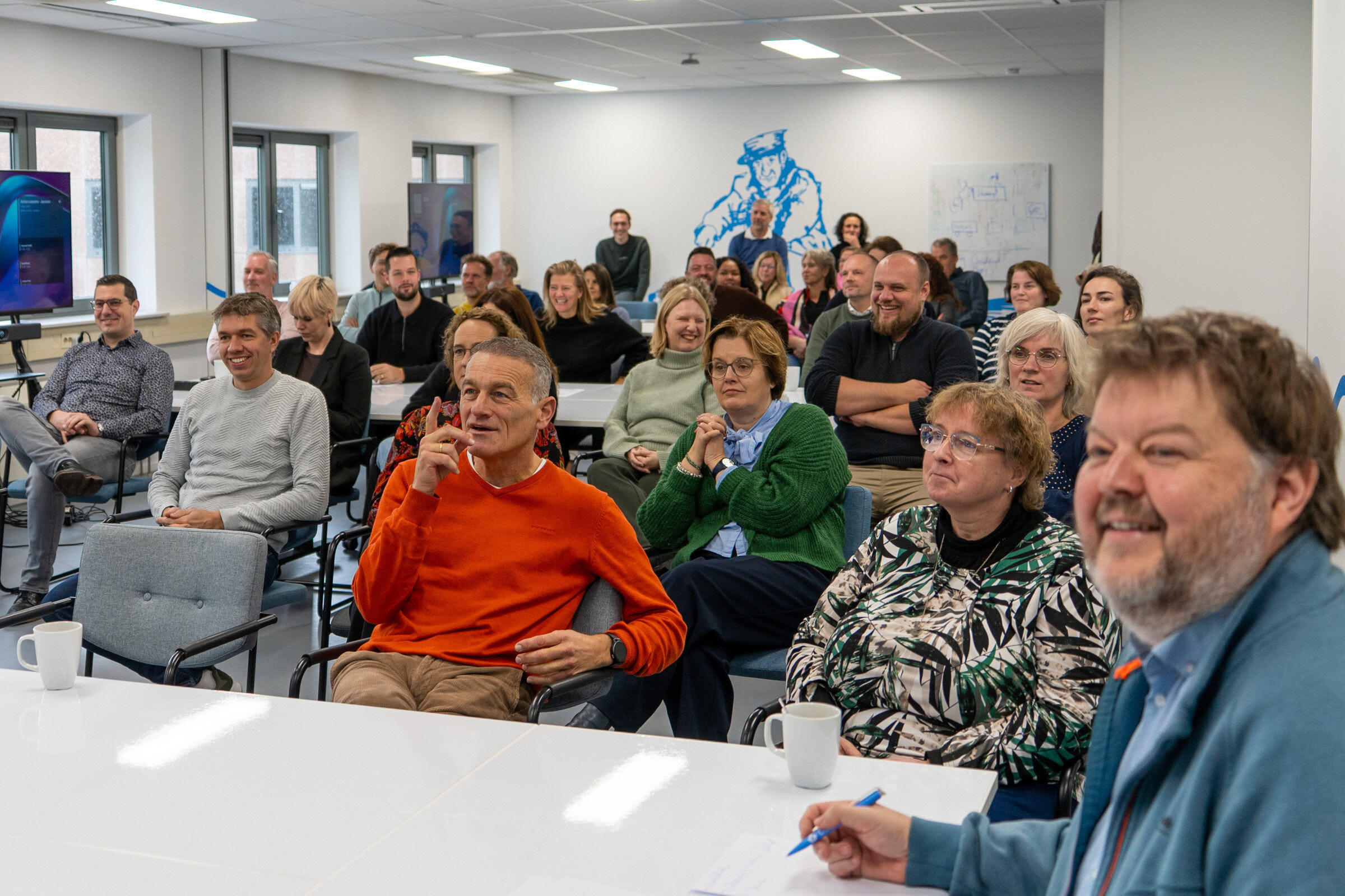 Een groep mensen die betrokken zijn bij Dorcas, een christelijk goed doel, tijdens een bijeenkomst in een goed verlichte, moderne ruimte.