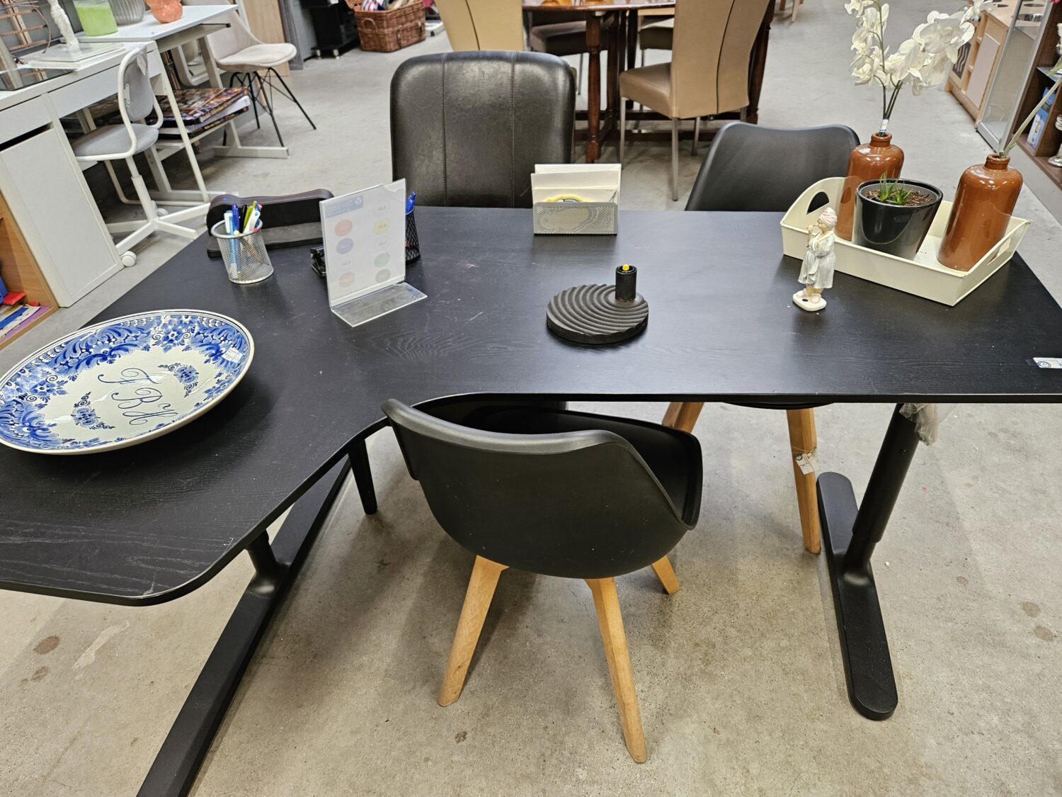 Een zwart tafel met diverse decoratieve items en stoelen in een interieurwinkel of kantoorruimte.