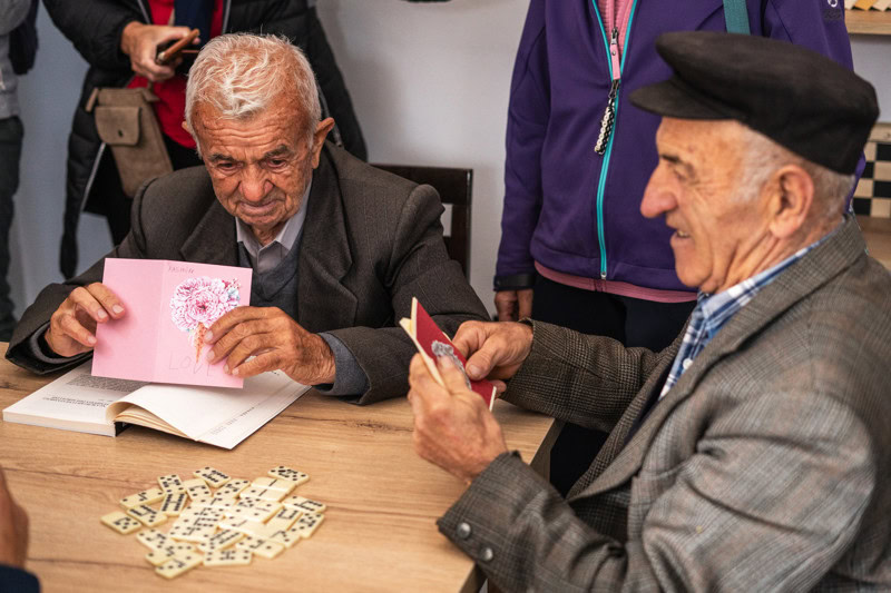 Een groep oudere mensen geniet samen van een bordspel, lachen en ontspannen in een warme, sociale omgeving.