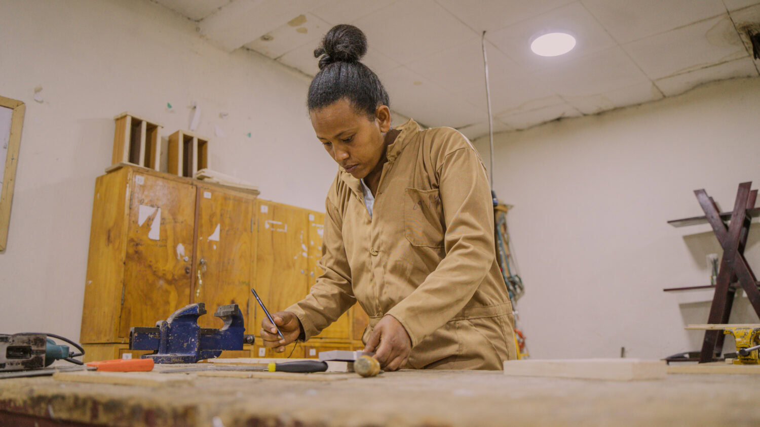 Een vrouw die nauwkeurig hout bewerkt in een werkplaats voor ambachtelijk vakmanschap.