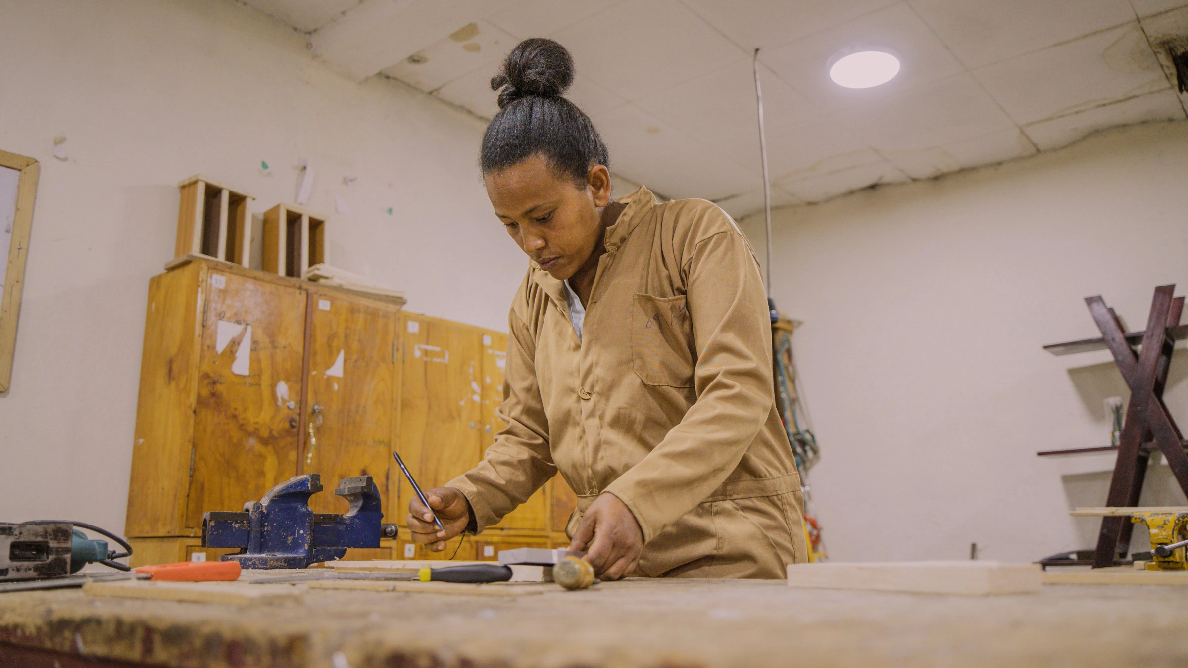 Een vrouw die nauwkeurig hout bewerkt in een werkplaats voor ambachtelijk vakmanschap.