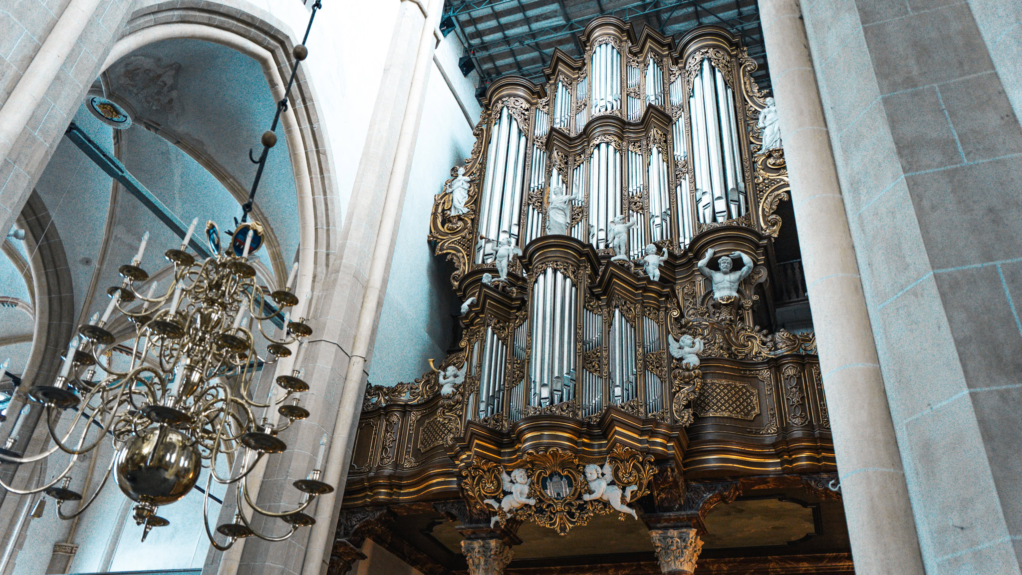 Gedetailleerde foto van een groot kerkorgel met gouden decoraties en een elegante kroonluchter in een oude kerk, passend bij het thema Psalmenmarathon.