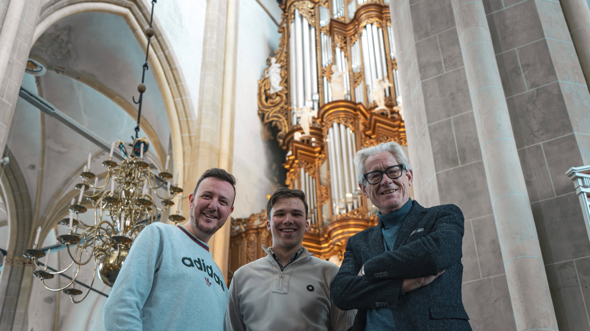 Drie mannen zingen samen tijdens Psalmenmarathon in een kerk met een groot orgel op de achtergrond.