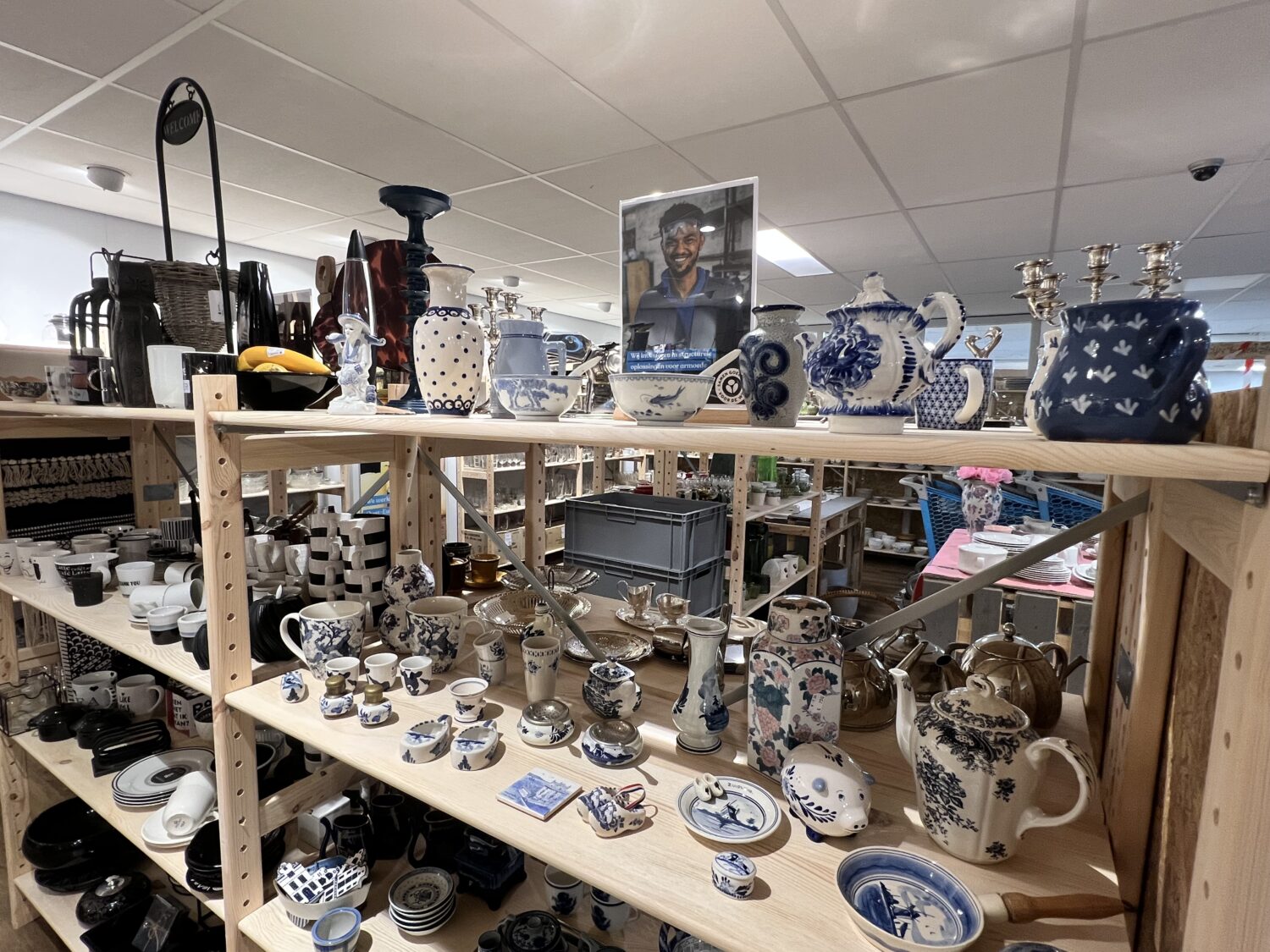 Een uitgebreide collectie Delfts blauw servies, theepotten en decoratieve items op houten rekken in een winkel.