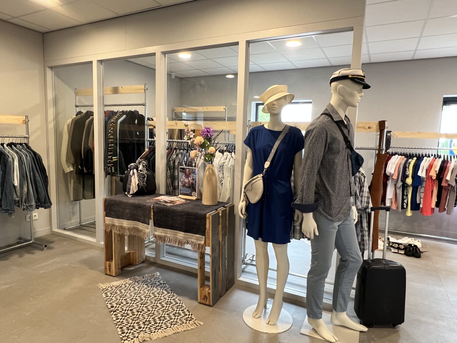 Drie mannequins met kleding en accessoires in een winkelruimte.