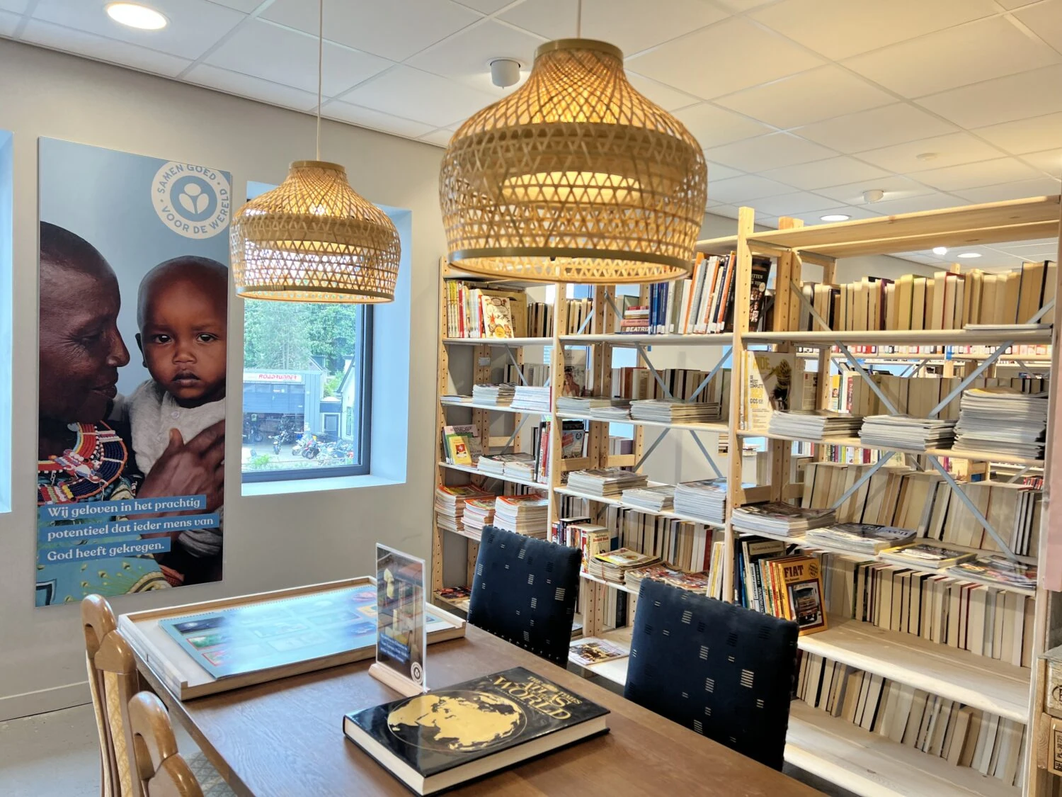 Een gezellige leeshoek met boekenplanken, tafels en stoelen in een bibliotheek of community center.