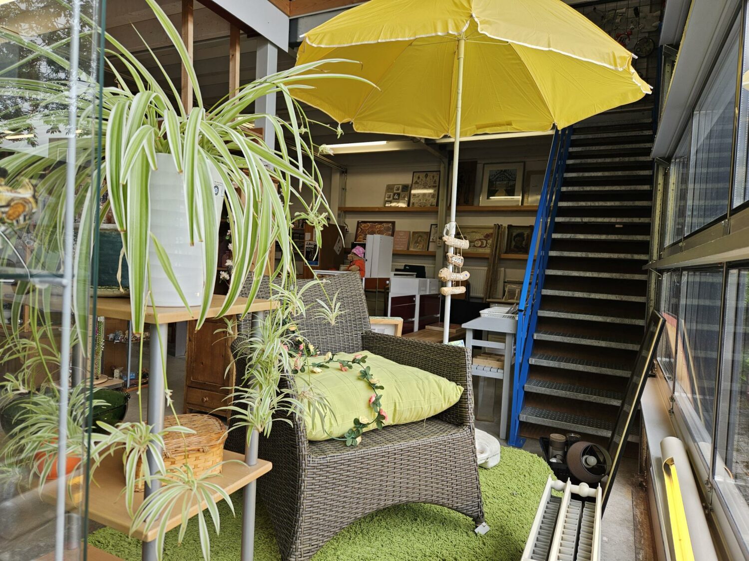 Gezellige zithoek met groene planten, een gele parasol en comfortabele stoelen in een interieur met veel natuurlijk licht, passend bij de missie van Dorcas voor humanitaire hulp en armoedebestrijding.