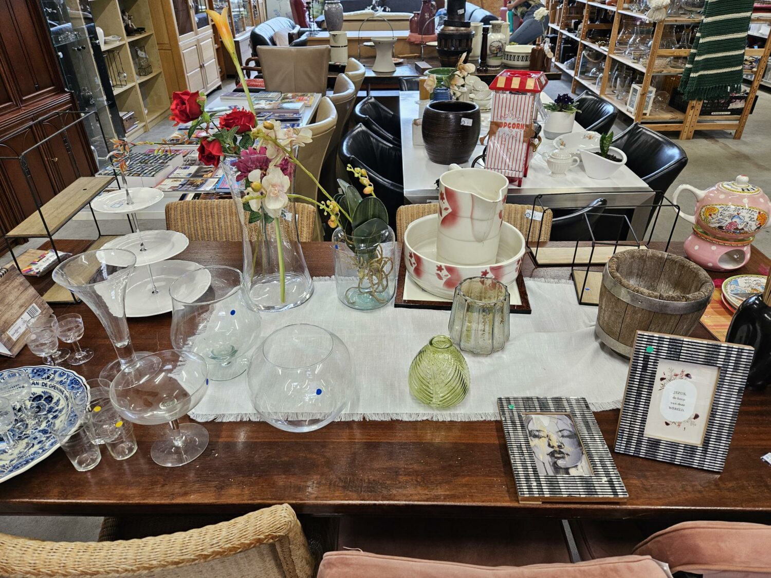 Diverse tweedehands woonaccessoires en servies op een tafel in een kringloopwinkel, symboliseert hergebruik en ondersteuning van humanitaire hulp door Dorcas.