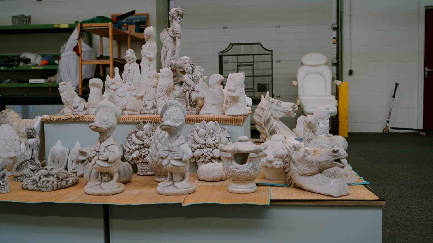 Onbehandelde betonnen sculpturen en decoraties voor een kunstproject of tuin, geplaatst op een tafel in een werkruimte, klaar voor afwerking of schilderen.