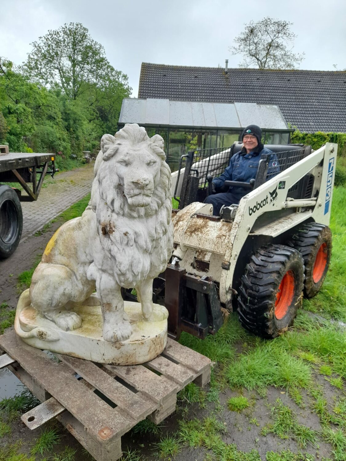 Een persoon in een rolstoel naast een grote betonnen leeuw, symbolisch voor kracht en hulp, bij een project voor Dorcas Aalten, gericht op humanitaire hulp en armoedebestrijding.