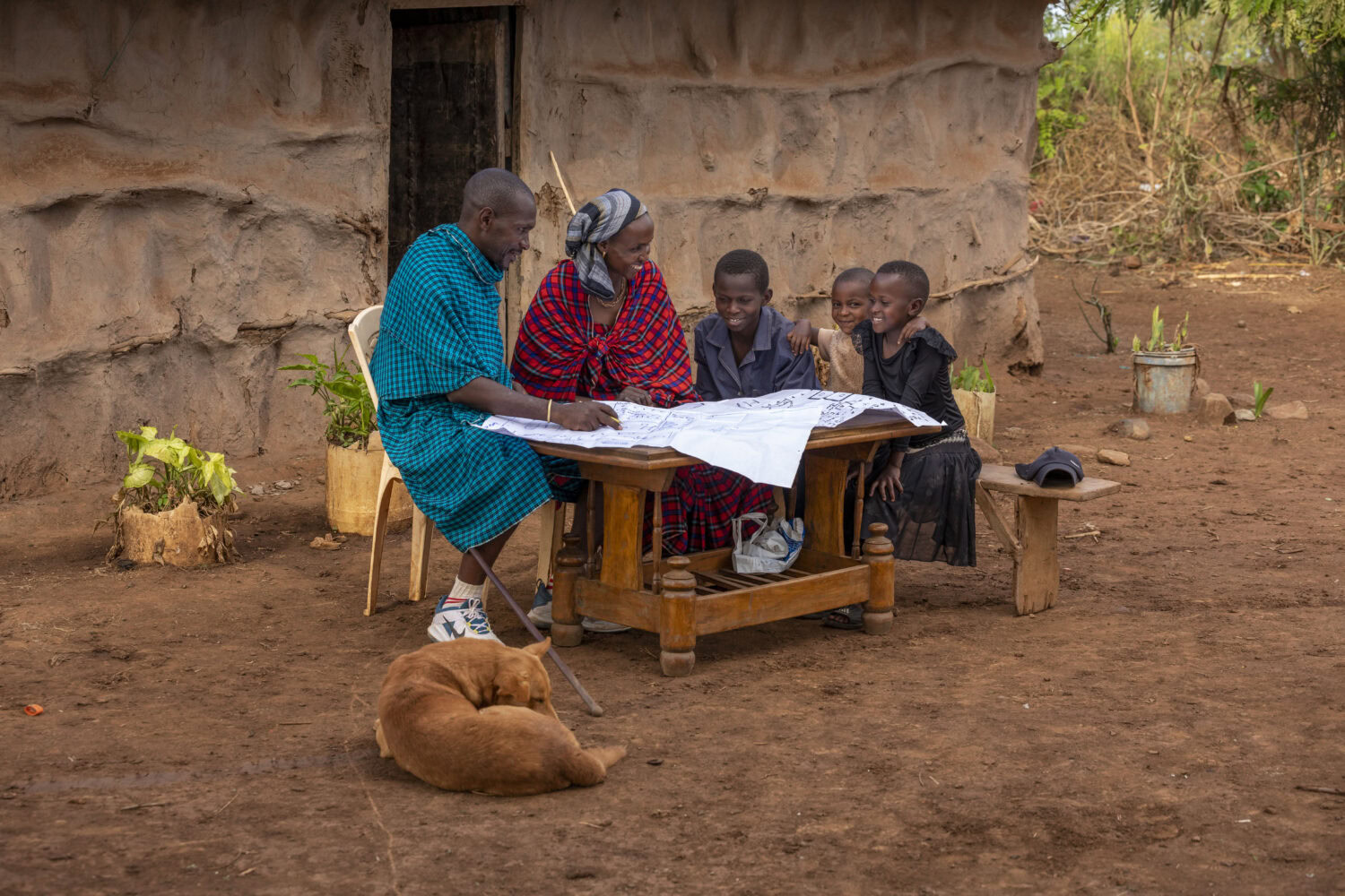 Hulpverleners en kinderen in een Afrikaanse gemeenschap leren samen lezen en schrijven, een voorbeeld van humanitaire hulp en armoedebestrijding door Dorcas.