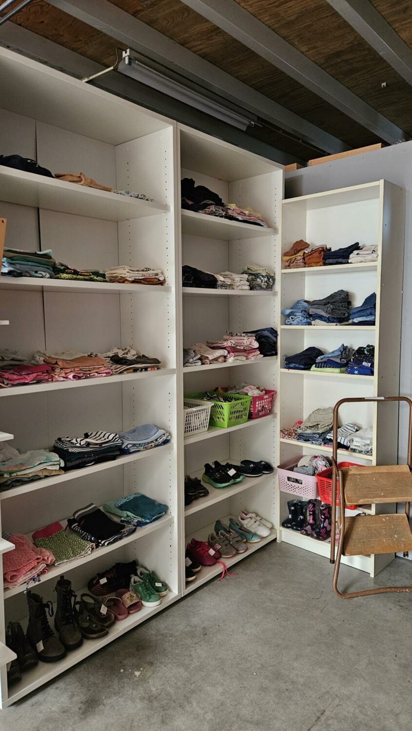 Ingerichte kledingkast met gesorteerde kleding, schoenen en accessoires, symboliseert hulp en ondersteuning in humanitaire projecten door Dorcas.