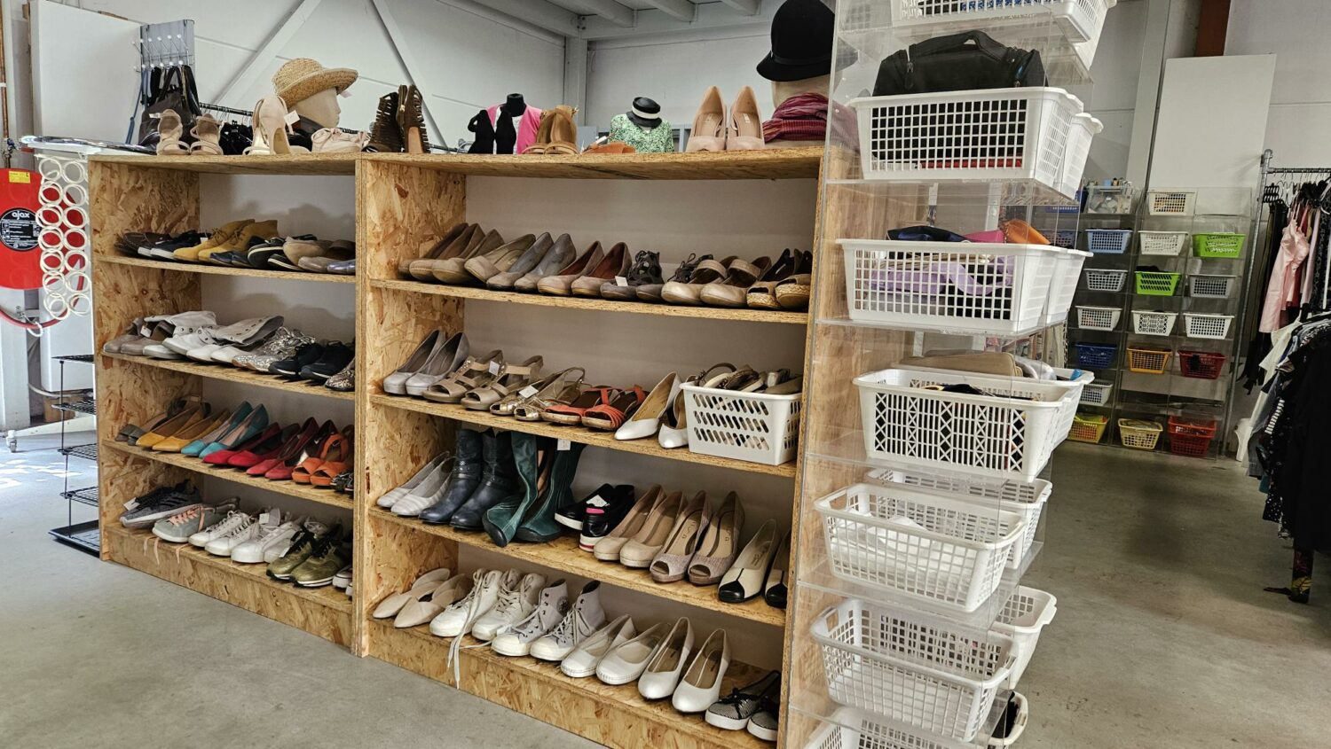 Tweedehands schoenen en accessoires op een houten winkelrek, geschikt voor humanitaire hulp en armoedebestrijding in ontwikkelingslanden, passend bij de missie van Dorcas.