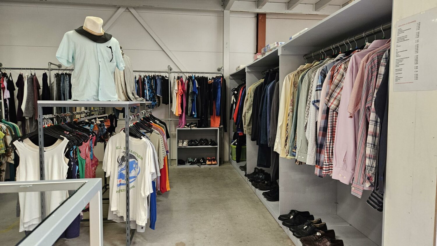 Binnenkijkje in een kledingwinkel met diverse kledingstukken en schoenen, gericht op humanitaire hulp en armoedebestrijding, passend bij de missie van Dorcas.