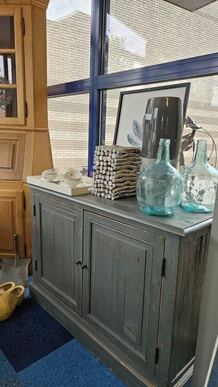 Decoratieve glazen flessen en handdoeken op een houten kast, symboliseert hulp en ondersteuning in humanitaire projecten van Dorcas.