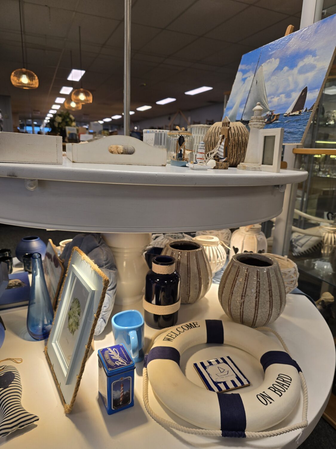 Decoratieve woonaccessoires en servies op een winkelvloer, met een nautisch thema en natuurlijke kleuren, passend bij humanitaire hulp en armoedebestrijding.
